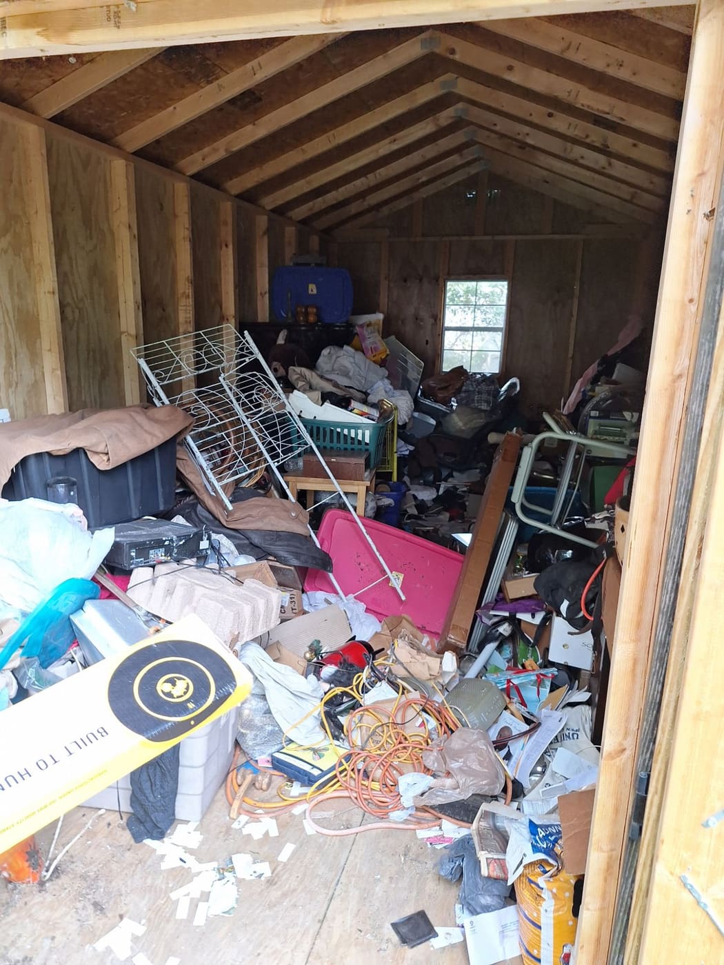 Inside a storage shed packed with boxes, bins, cords and debris before cleanout